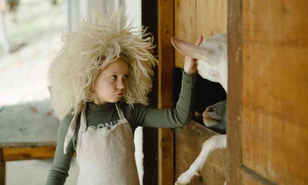 Das Bild zeigt ein Kind in Wollkleidung und visualisert ein Teil der behandelten neun außergewöhnliche Eigenschaften von Wolle und ihre Verwendung.