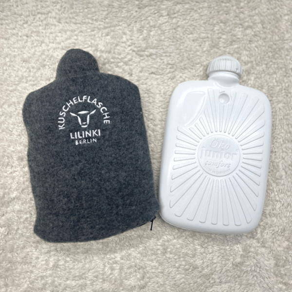 Grauer Wärmflaschenbezug aus Schurwolle neben der Öko-Juniorflasche.